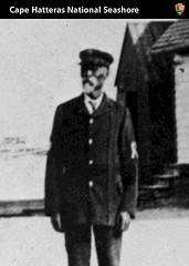 A historical black and white photograph of Captain Richard C. Etheridge standing outside of the Pea Island Lifesaving Station.