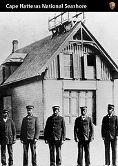 A historical black and white photo of the Pea Island Surfmen standing in front of the Pea Island Lifesaving Station.