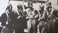 5 Members of the Tuskegee Airmen stand in front of an airplane