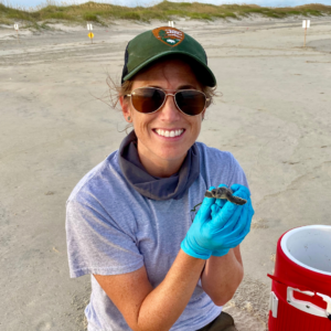 Ranger Amy holds a sea turtle hatchling on Cape Hatteras National Seashore