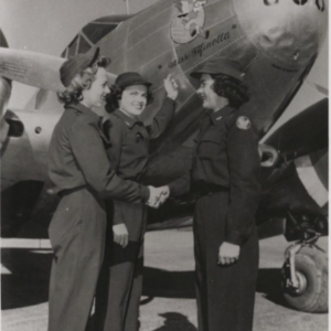 Three Women Airforce Service Pilots (WASPs) shaking hands in front of airplane. 