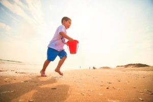 A young boy runs with a red bucket on Cape Hatteras National Seashore.