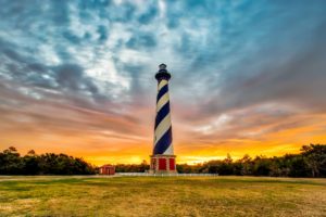 A color photograph of the Cape Hatteras Lighthouse captured at sunset. 
