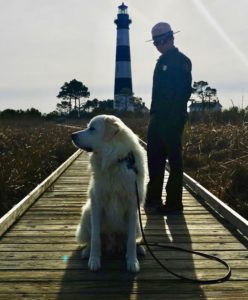 Ranger Thomas with his dog and B.A.R.K Ranger, Jackson, on the boardwalk in front of the Bodie Island Lighthouse.