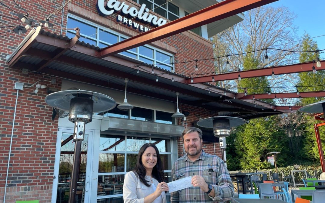 Jessica Barnes (left), director of Outer Banks Forever, and Robert Poitras, founder and CEO of Carolina Brewery, hold a check from Carolina Brewery to Outer Banks Forever for Giving Tuesday.