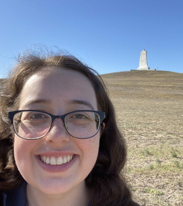 Conservation Intern Madison Grigsby at Wright Brothers National Memorial with the Wright Brothers Monument in the background.