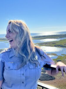 Ranger Taylor at the top of the Bodie Island Lighthouse. An iron railing and marshlands can be seen in the background.
