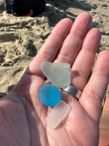 A hand holding blue, green, and white sea glass.